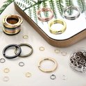 Set met sleutelringen in goud, roségoud, zilver, zwart en brons, op een spiegelende ondergrond.