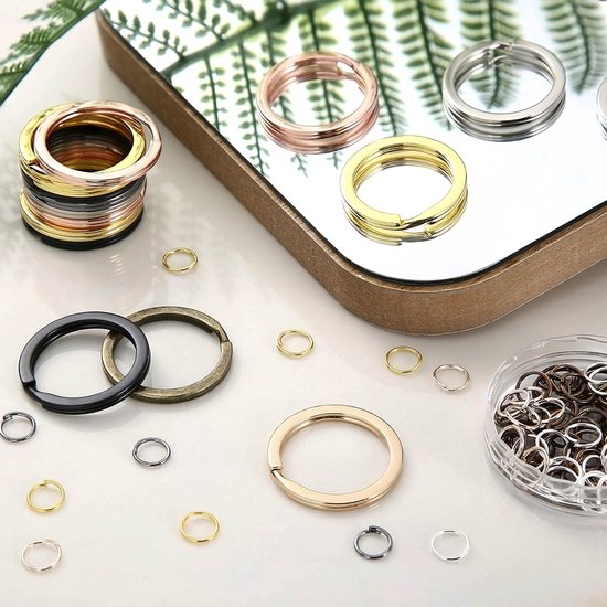 Set met sleutelringen in goud, roségoud, zilver, zwart en brons, op een spiegelende ondergrond.
