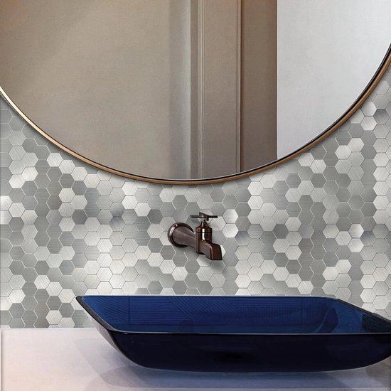 Zilverkleurige hexagon tegels met geborstelde afwerking, op een badkamermuur met ronde spiegel en blauwe wastafel.
