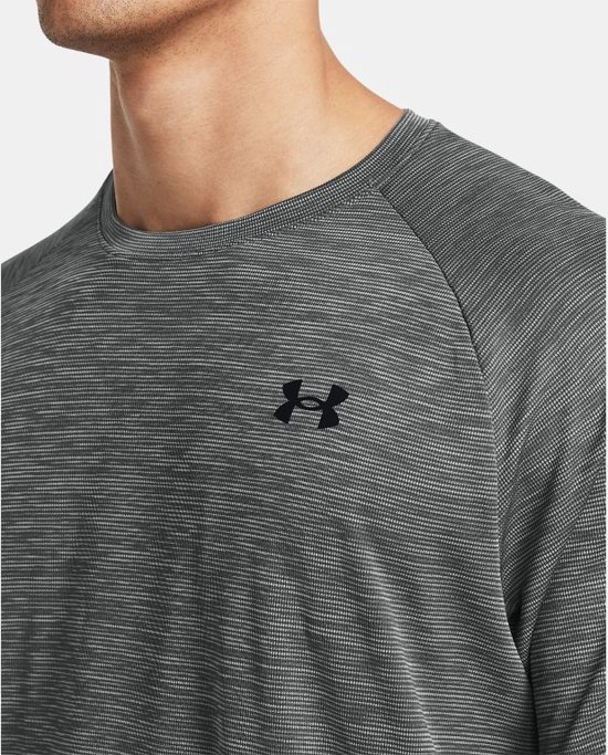 Gedetailleerde voorkant van een grijs sportshirt met fijne horizontale strepen en zwart Under Armour logo.