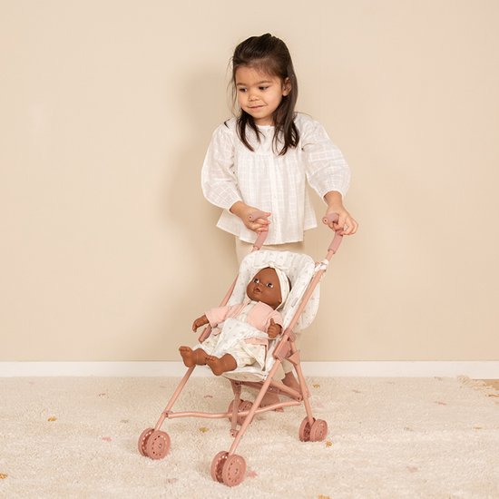 Een kind met witte blouse en beige broek duwt een roze poppenbuggy met een pop met roze jasje.