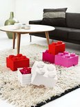 Vier stapelbare rode en roze Lego-opbergblokken en een wit opbergblok met bloemen.