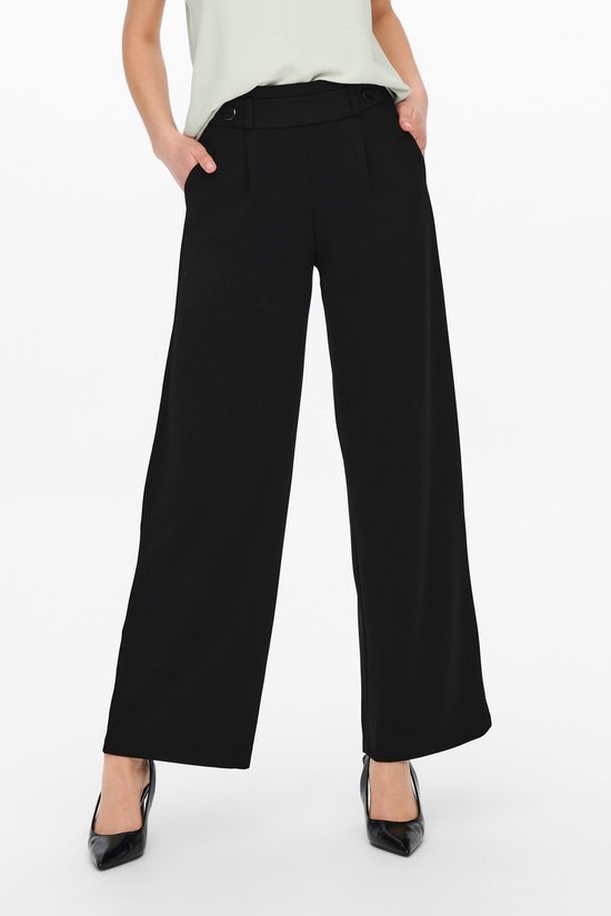 Model draagt zwarte wijde broek met hoge taille en knopen.