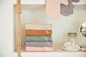 Stapel van zes badcapes in beige, bruin, groen, grijs en roze, naast een spiegel.