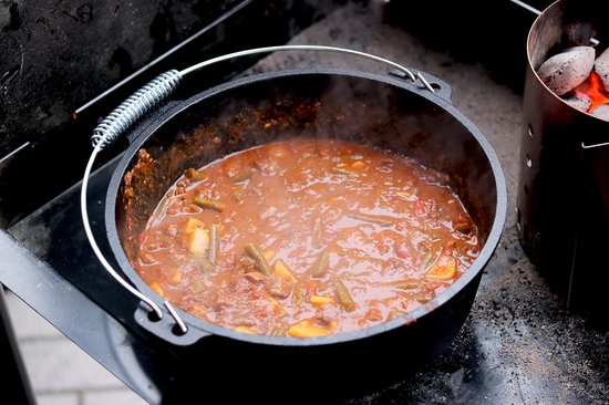 Gietijzeren Dutch oven gevuld met stoofpot, met aardappelen en sperziebonen.
