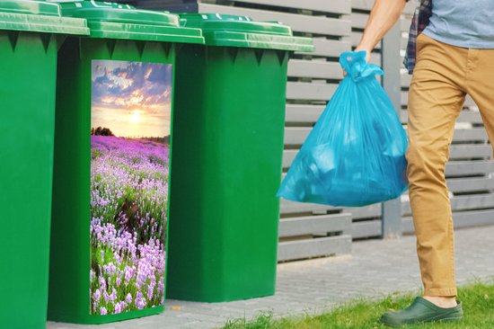 Groene kliko met sticker van paarse lavendelweide, zonsondergang. Man gooit vuilniszak weg.