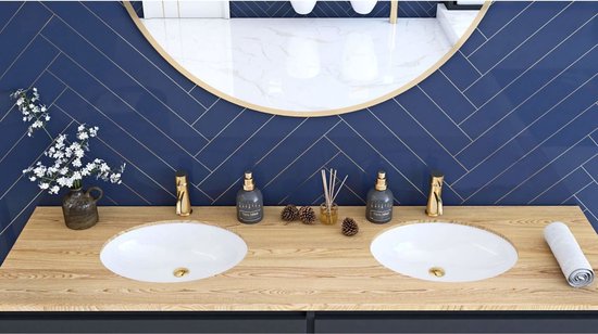 Lavabo double avec robinets dorés, entouré d'un miroir à bordure dorée et de carreaux bleu marine en chevrons.