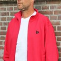 Close-up van een man met rood trainingsvest met rits en zwart logo, met witte T-shirt eronder.