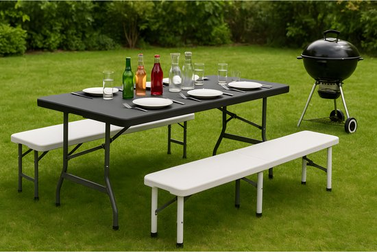 Zwarte klaptafel met witte bankjes in de tuin, gedekt met flessen en glazen.