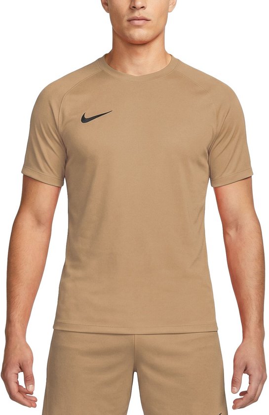 Man met lichtbruin Nike sportshirt met zwarte swoosh. Het shirt heeft een ronde hals en korte mouwen. Hij draagt een bijpassende korte broek.
