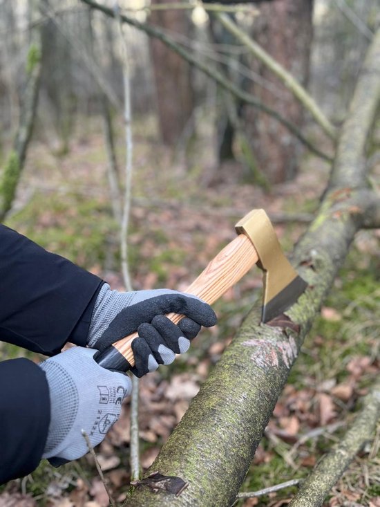 Grijze werkhandschoenen houden een handbijl vast met lichtbruin houten handvat en messingkleurige kop, terwijl deze een boomstronk raakt.