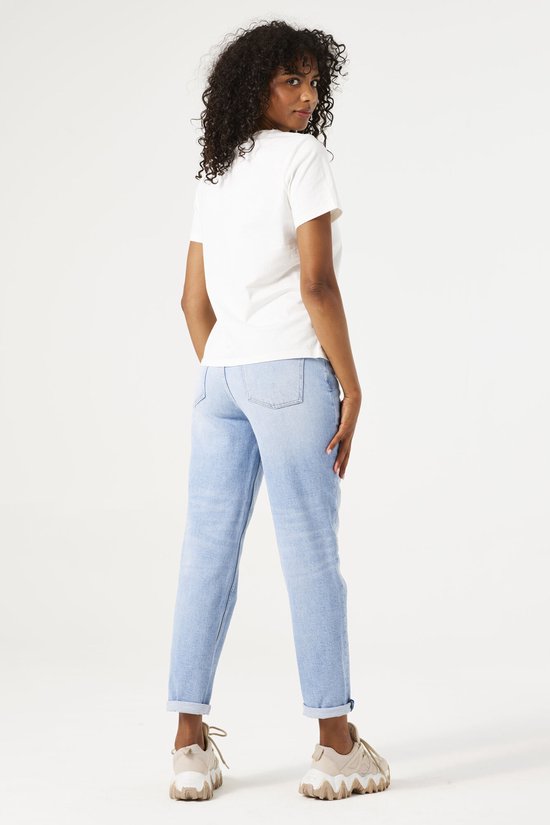 Achterkant van een model in een witte T-shirt en lichtblauwe mom fit jeans.
