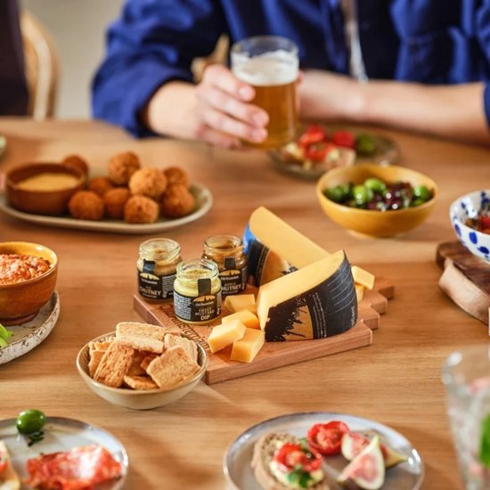 Een tafel vol Old Amsterdam kaas, met dips, olijven, snacks en drankjes.