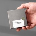 Hand die een grijs doosje van Trendhim Accessories vasthoudt, met "Made in Denmark" op de voorkant.