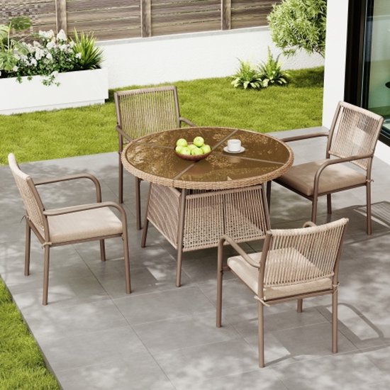 Bruine rotan tuinset met ronde glazen tafel in een tuin.