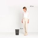 Vrouwen van 167 cm bij een licht beige afvalbak van 35 cm hoog.