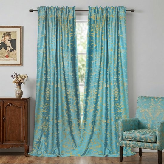 Luxe turquoise fluwelen gordijnen met goudprint hangend voor een raam, naast een stoel en een dressoir.
