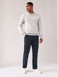Model draagt een marineblauwe chinobroek, grijze trui en witte sneakers.