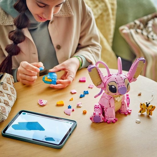Une femme construit la LEGO Angel avec nœud, assise à une table avec une tablette.