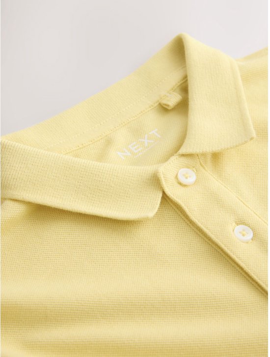 Close-up van de kraag en knoopjes van een lichtgeel poloshirt met korte mouwen.
