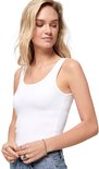 Close-up van een vrouw met een witte tanktop met spaghettibandjes, spijkerbroek en ringen.