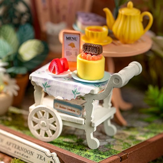 Close-up van miniatuur dienblad met gebak, aardbeien en snoep. De rolly street is zichtbaar.