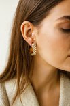 Gouden oorringen met witte parels, gedragen door een model.