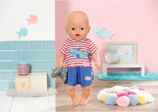 BABY born pop met rood-wit gestreepte pyjamaset met haaiendetails en grijze schoentjes. Een grijze haaienspeeltje in de hand.