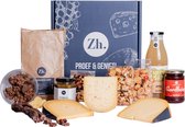 Een borrelpakket met kazen, worst, crackers, sap en jam, met een papieren zak en een geschenkdoos.