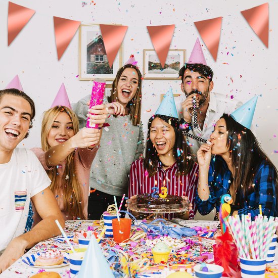 Un groupe de jeunes joyeux célèbre un anniversaire avec des chapeaux de fête, des confettis et un gâteau avec une bougie.