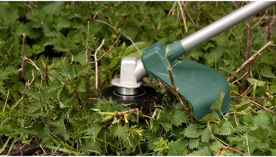 Grastrimmer kop die brandnetels snijdt met een groene beschermkap.