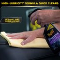 Une main utilise un spray détaillant intérieur Meguiar's avec une lingette jaune sur un siège de voiture en cuir.