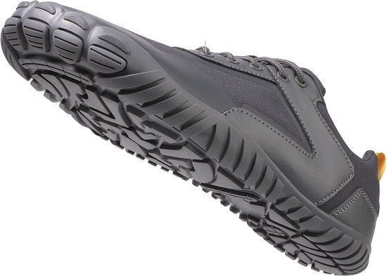 Chaussure minimaliste grise en l'air, vue de côté en biais avec semelle à crampons.