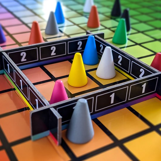 Close-up van HUES AND CUES spel. Geel, roze, blauw, grijs en oranje pionnen op een raster van kleuren met cijfers 1 en 2.