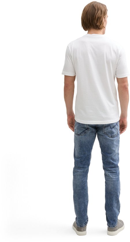 Man in wit T-shirt en slanke, lichtblauwe spijkerbroek, gezien van achteren.
