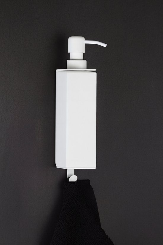 Witte zeepdispenser aan de muur met een zwarte handdoek die eraan hangt.