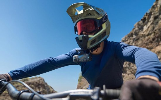 Een mountainbiker met helm en skibril filmt zichzelf met een Insta360 camera op de borst.