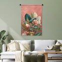 Een wandkleed met tropische bladeren in groen-, crème- en roze tinten, hangend in een woonkamer met een witte bank en fauteuils.