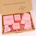 Boîte cadeau My Bendel ouverte avec des boîtes et des pochettes à bijoux roses.