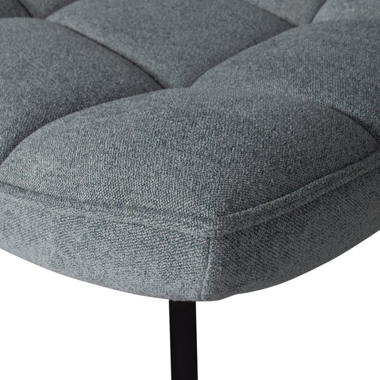 Gedetailleerde close-up van de lichtblauwe stof met geblokt stikpatroon op de hoek van een fauteuil.