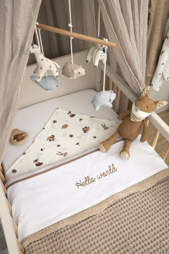 Wieg met een mobiel met dierenfiguren, een deken met bosdierenprint en tekst 'Hello world'.