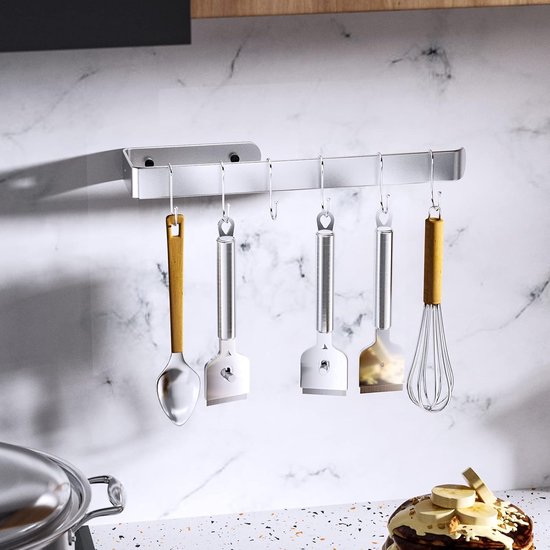 Zilveren kookplaatschrapers met houten en metalen handvatten hangend aan een keukenrek.