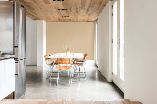 Eettafel met zes oranje stoelen met metalen frame, in een lichte eetkamer met houten plafond en beige muur.