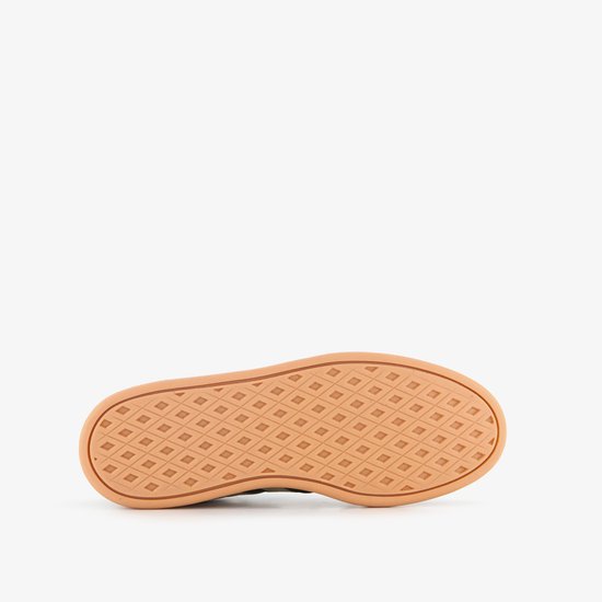 De beige buitenzool met ruitpatroon van een zwarte Adidas sneaker.