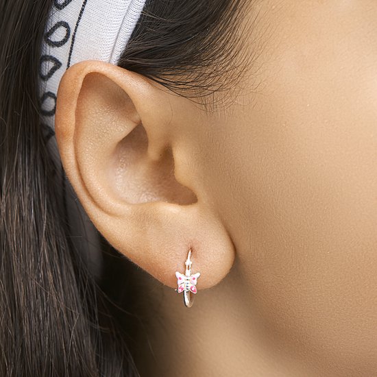 Een zilverkleurige oorring met roze vlinder op een kinder oor.