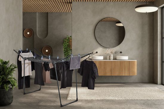 Étendoir noir avec vêtements, serviette et cintres dans une salle de bain.