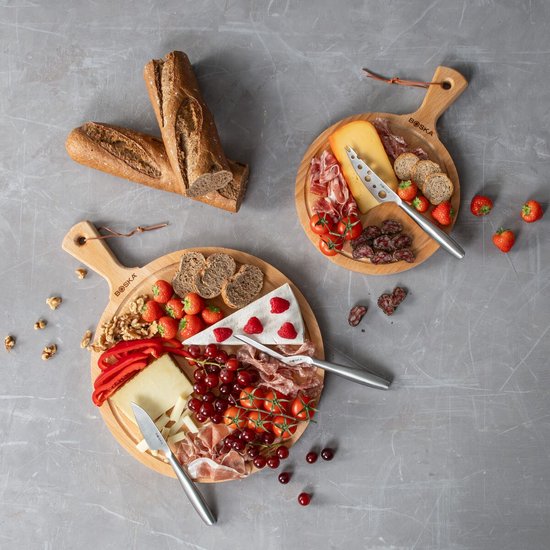 Deux planches de service en bois avec du fromage, de la charcuterie, des fruits et du pain. Une planche est garnie de brie, fraises et raisins. L'autre de fromage jeune, salami et tomates.