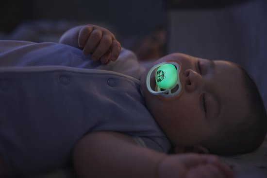Baby slaapt met een gloeiende, lichtgroene Philips Avent Ultra Air fopspeen met libelpatroon.