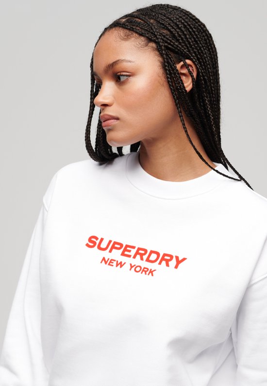 Gros plan d'un sweat blanc avec l'inscription rouge "SUPERDRY NEW YORK".