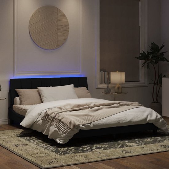 Cadre de lit noir avec tête de lit rembourrée et éclairage LED, fait dans une chambre.